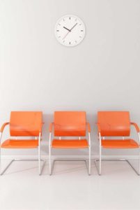 Orange chairs and white clock in waiting room