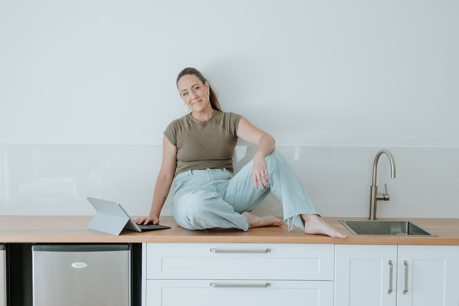 Robyn sitting on the kitchen counter with her laptop beside her