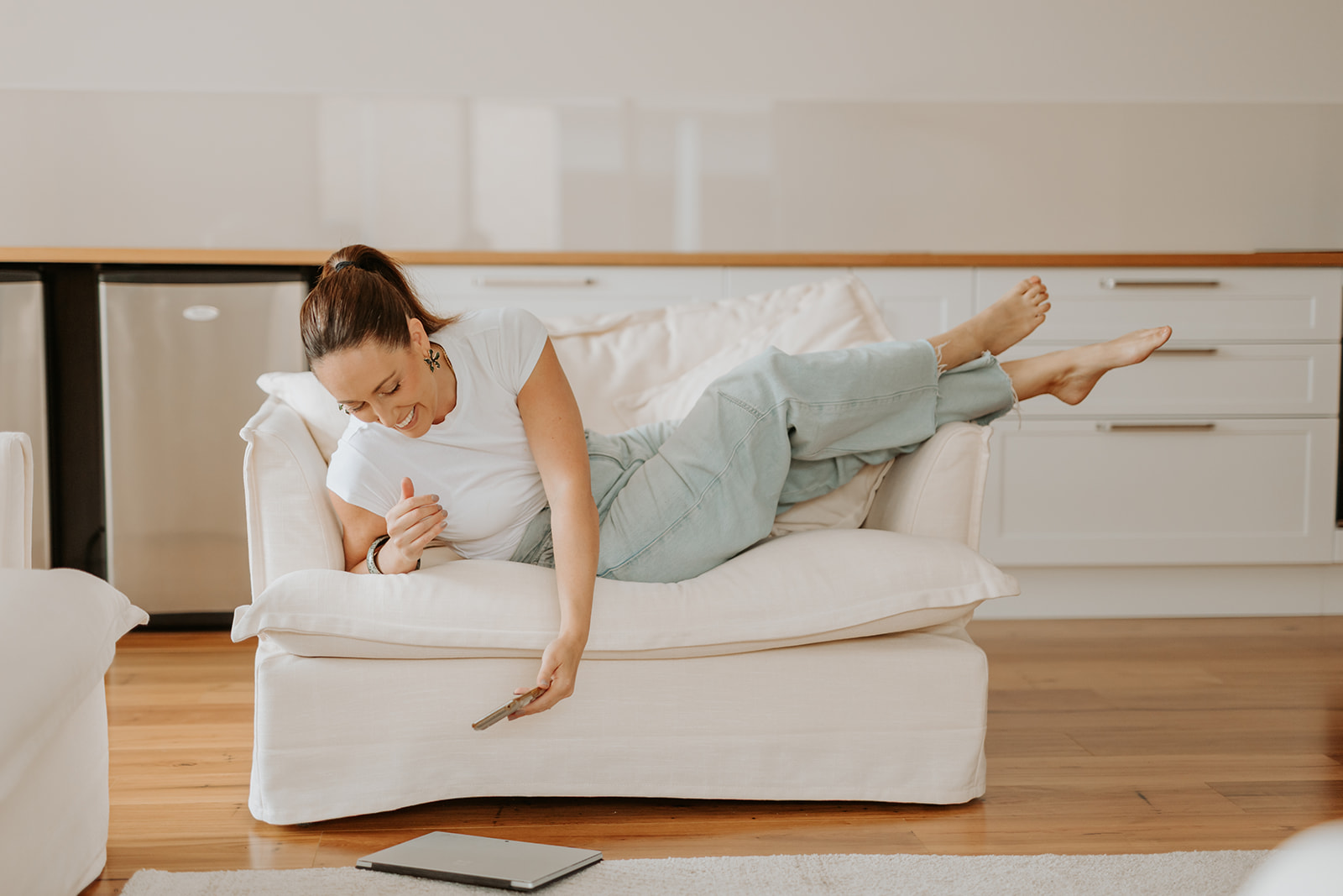 Robyn Birkin lying on the sofa, reaching for her phone