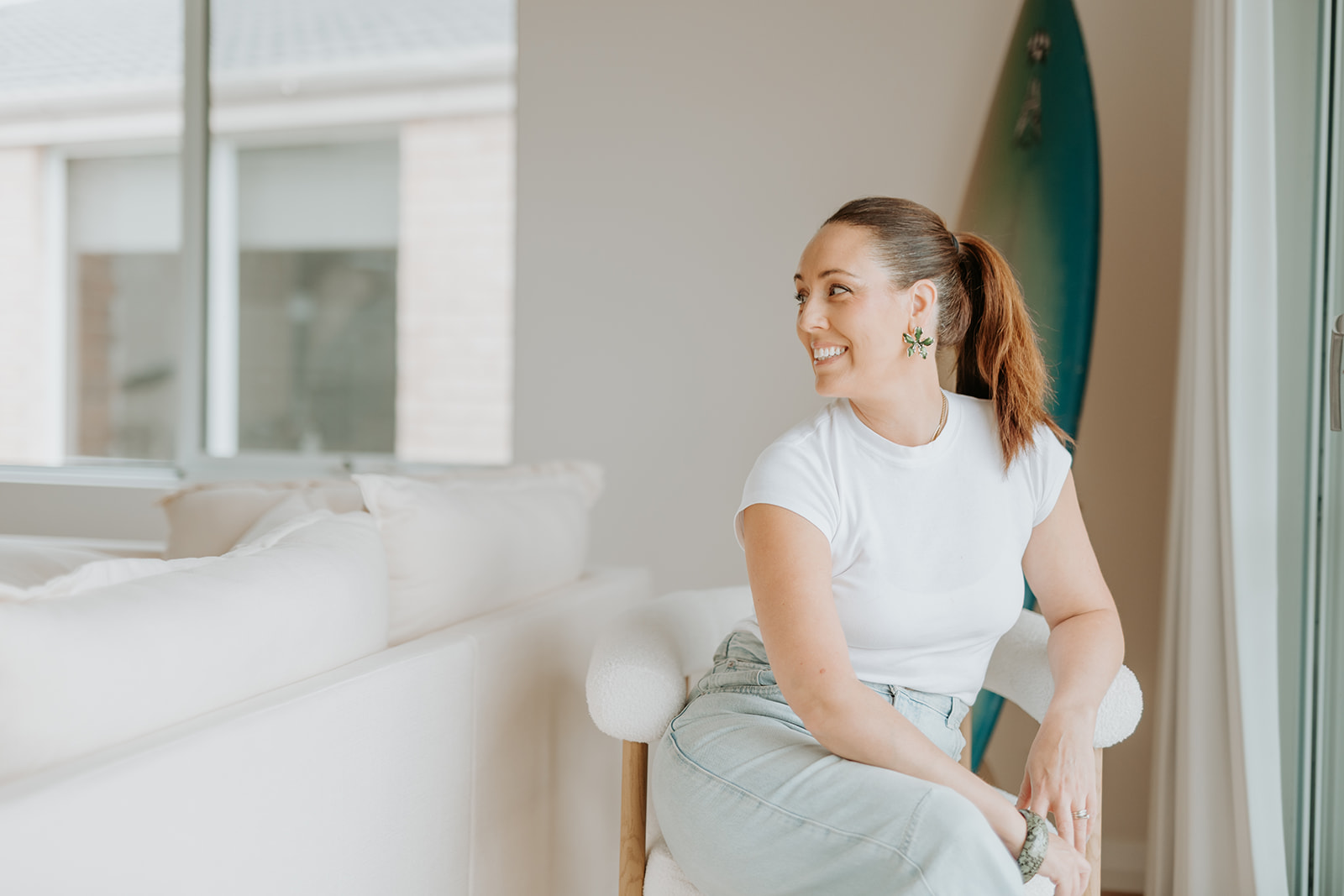 Robyn in a white shirt on a white chair, looking to the side